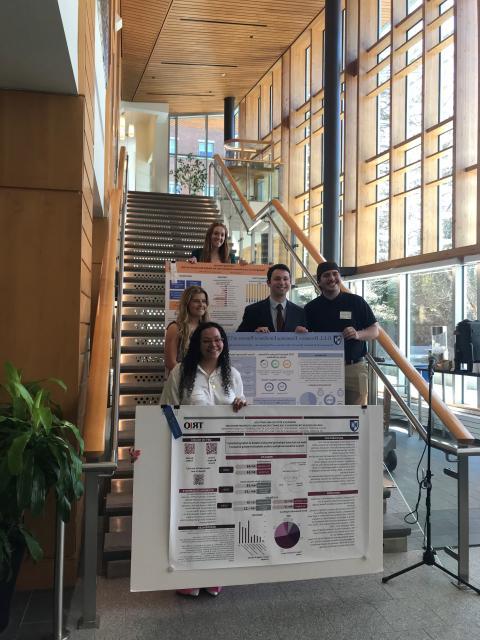 Students standing on staircase with ribbon-winning research posters